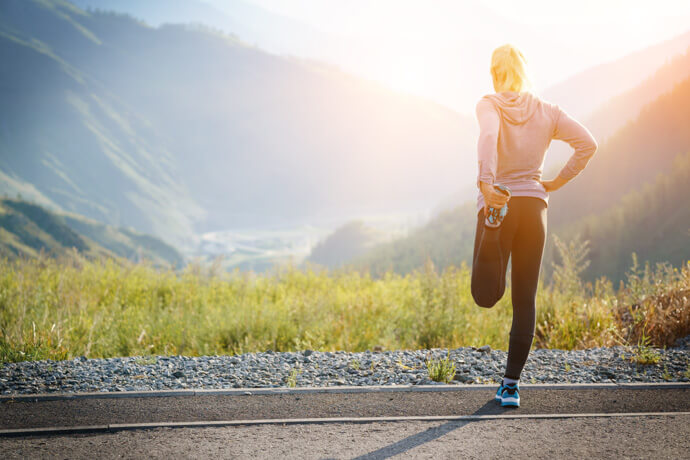 mujer deportista haciendo estiramientos de cara a la montaña