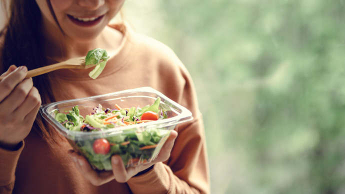 Mujer comiendo una ensalada durante su dieta cardiosaludable.